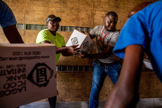 Two men carrying boxes in a warehouse environment, demonstrating teamwork.