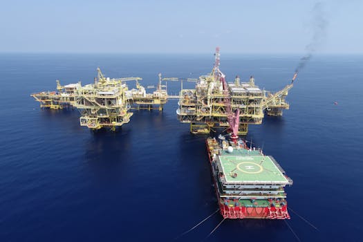 Aerial shot of multiple offshore oil platforms in a serene, blue sea under clear skies.